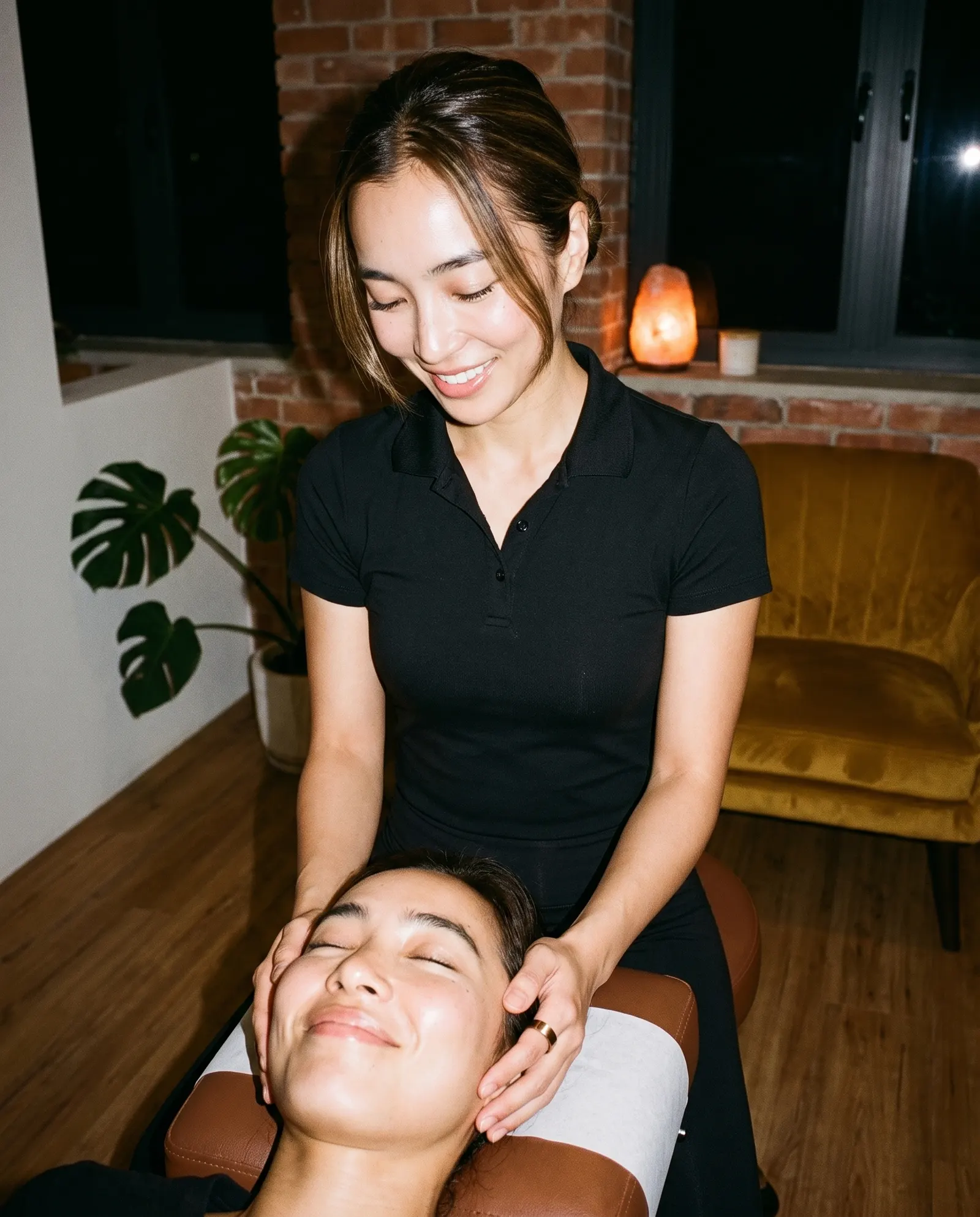 A chiropractor wearing a ChiroRing smiles while cradling a practice member's head on the table